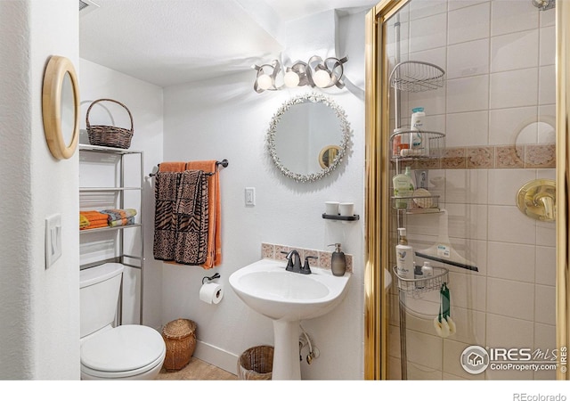 2310 44th Ave, Greeley, CO 80634 - bathroom featuring toilet, baseboards, a shower with shower door, and a sink