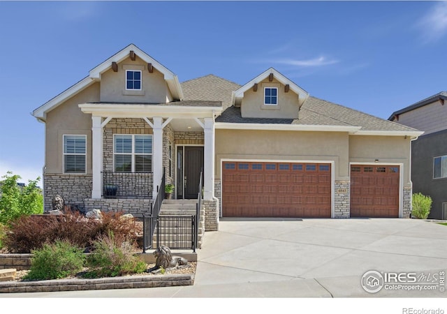 4843 Mariana Hills Cir, Loveland, CO 80537 - view of front of home with stone siding, an attached garage, stucco siding, and driveway
