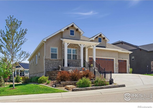 4843 Mariana Hills Cir, Loveland, CO 80537 - view of front of house with stone siding, stucco siding, a garage, and covered porch