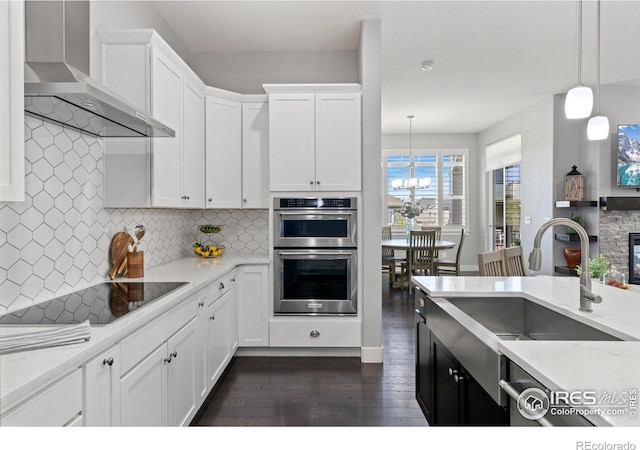 4843 Mariana Hills Cir, Loveland, CO 80537 - kitchen featuring wall chimney exhaust hood, a sink, black electric cooktop, double oven, and dark wood finished floors