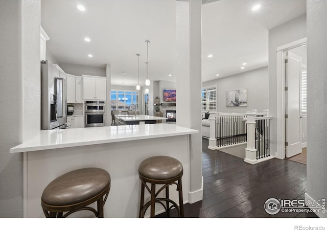 4843 Mariana Hills Cir, Loveland, CO 80537 - kitchen with dark wood finished floors, recessed lighting, light countertops, white cabinetry, and a peninsula