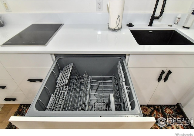 kitchen view of a sink, dishwasher, and wood finished floors