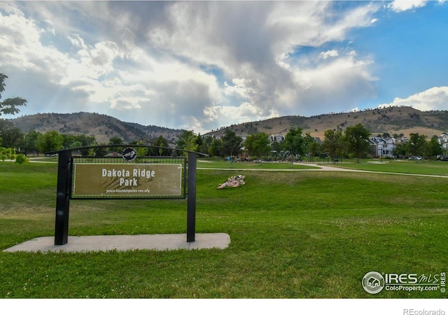 community sign with a mountain view and a yard