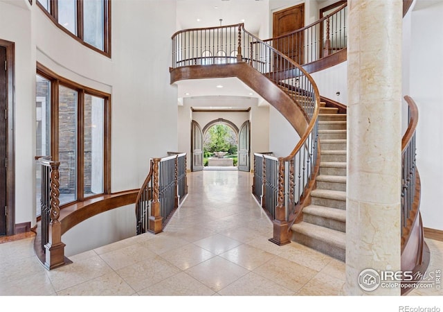 entryway with a towering ceiling, baseboards, and stairway
