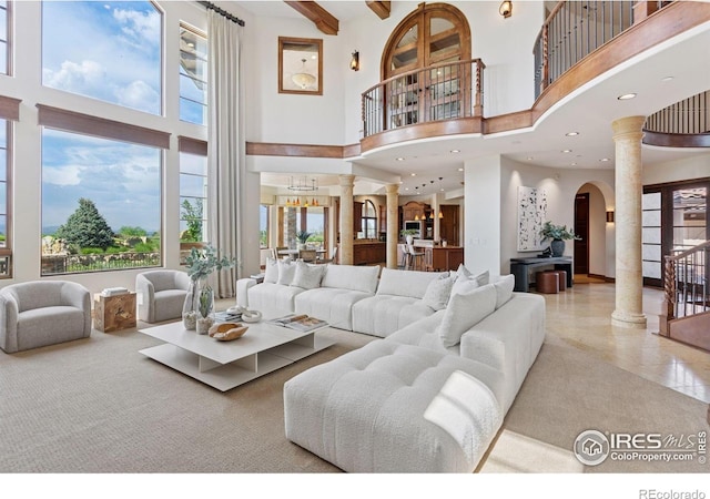 living room featuring decorative columns, a towering ceiling, healthy amount of natural light, arched walkways, and recessed lighting