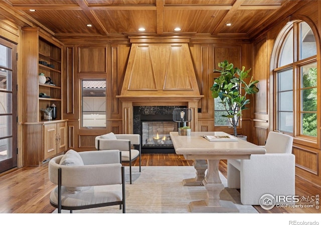 office area with wood ceiling, wood walls, a high end fireplace, light wood-type flooring, and built in shelves