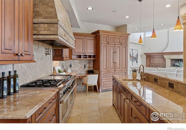 kitchen with double oven range, a sink, custom range hood, brown cabinetry, and decorative backsplash