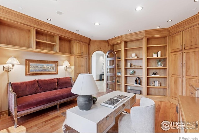 living room featuring arched walkways, light wood-type flooring, recessed lighting, and built in shelves