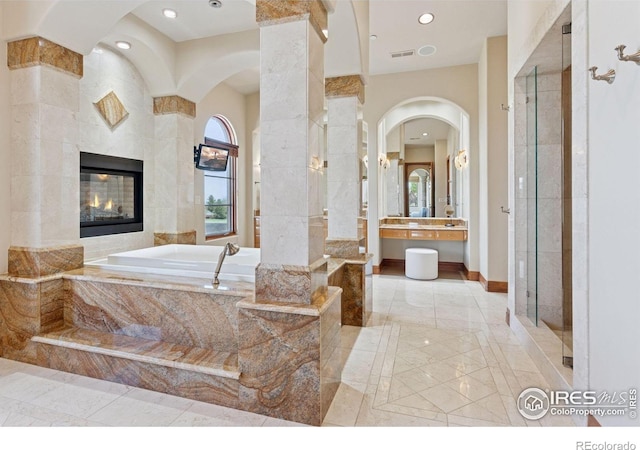full bathroom with marble tiled flooring, a garden tub, a shower stall, recessed lighting, and a tiled fireplace