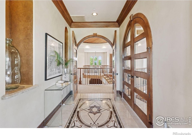 corridor with inlaid floor details, french doors, crown molding, baseboards, and arched walkways