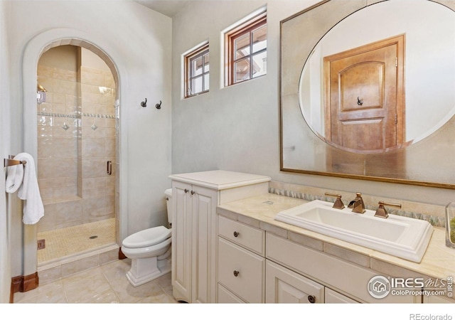 bathroom with toilet, a stall shower, and vanity
