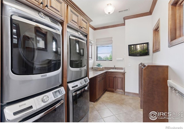 laundry room featuring stacked washing machine and dryer, crown molding, and light tile patterned floors