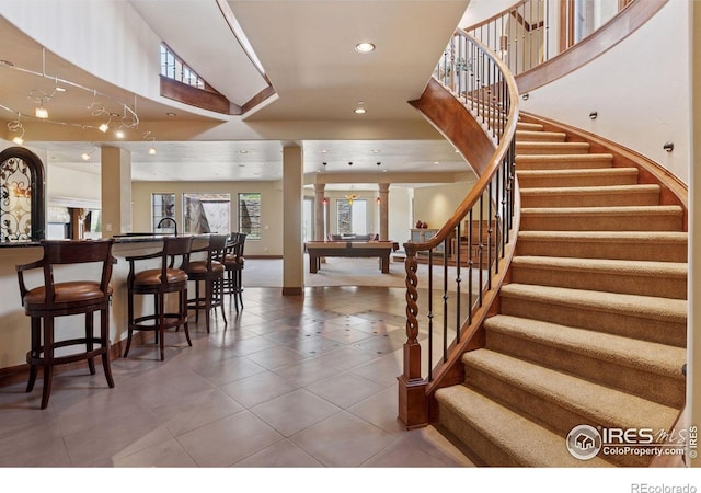 stairs with decorative columns, tile patterned flooring, a high ceiling, recessed lighting, and baseboards
