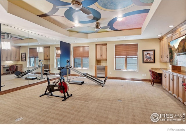exercise room featuring a tray ceiling, light carpet, a ceiling fan, baseboards, and recessed lighting