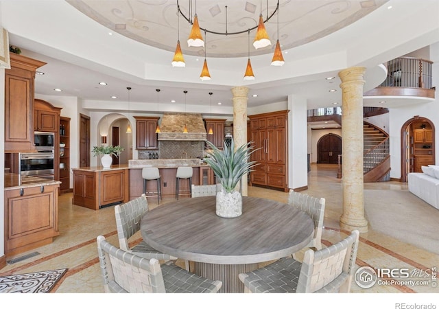 dining space with recessed lighting, ornate columns, inlaid floor details, stairway, and a raised ceiling