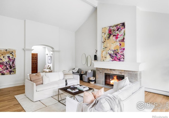910 Kalmia Ave, Boulder, CO 80304 - living area with arched walkways, decorative columns, a tiled fireplace, wood finished floors, and high vaulted ceiling
