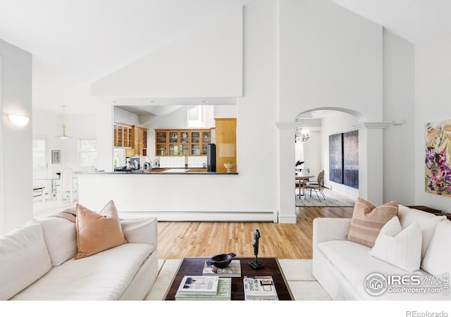 910 Kalmia Ave, Boulder, CO 80304 - living room featuring high vaulted ceiling, arched walkways, a baseboard heating unit, wood finished floors, and decorative columns