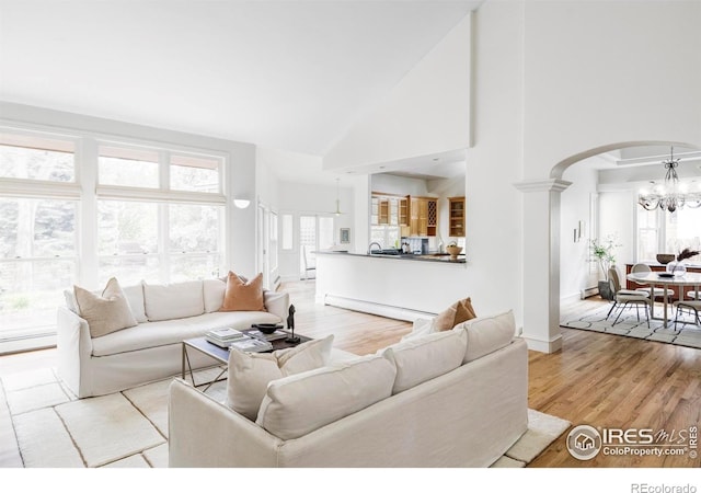 910 Kalmia Ave, Boulder, CO 80304 - living area featuring a chandelier, healthy amount of natural light, high vaulted ceiling, light wood-style floors, and ornate columns