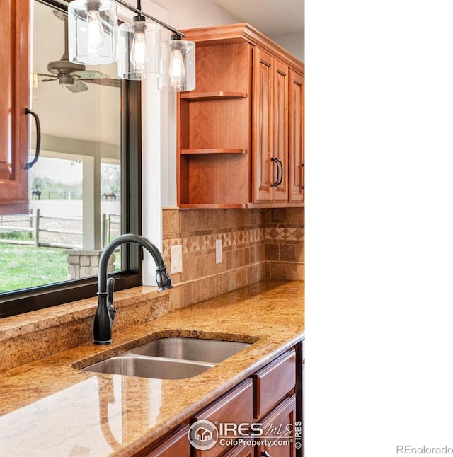2017 Vaquero St, Longmont, CO 80504 - kitchen featuring a sink, decorative backsplash, light stone counters, open shelves, and brown cabinets
