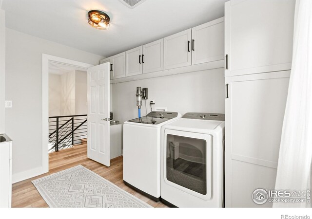 2017 Vaquero St, Longmont, CO 80504 - laundry area featuring independent washer and dryer, cabinet space, light wood-type flooring, and baseboards