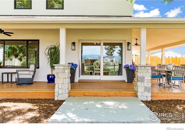 2017 Vaquero St, Longmont, CO 80504 - doorway to property with stucco siding, fence, a ceiling fan, outdoor dining area, and a deck