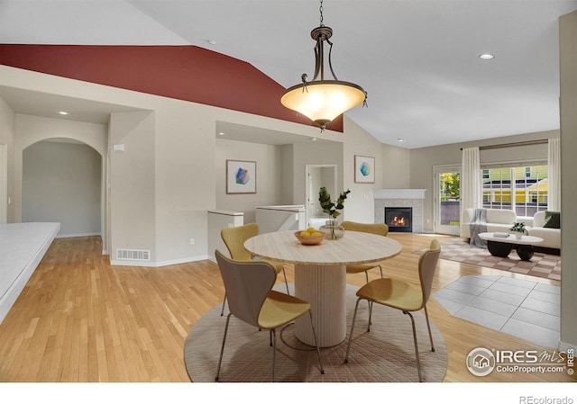 3742 Florentine Cir, Longmont, CO 80503 - dining room featuring a fireplace, arched walkways, light wood-style floors, high vaulted ceiling, and baseboards