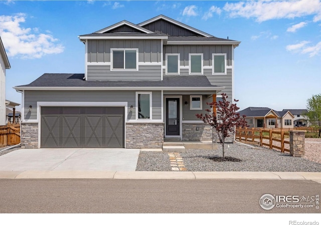 view of front of property featuring fence, board and batten siding, driveway, and stone siding
