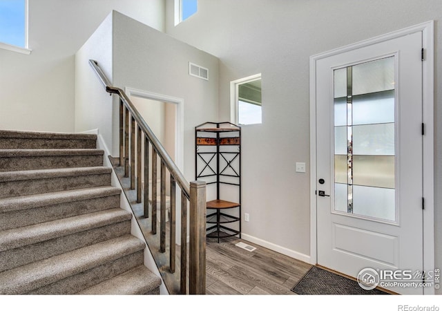 entryway featuring wood finished floors, stairs, and baseboards
