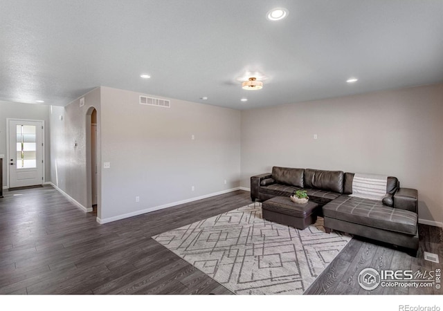 living room with wood finished floors, baseboards, arched walkways, and recessed lighting