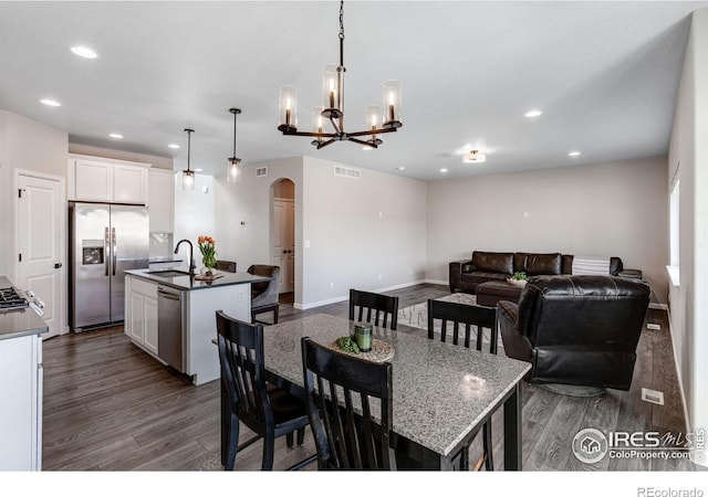 dining space with arched walkways, dark wood-style floors, recessed lighting, baseboards, and a chandelier