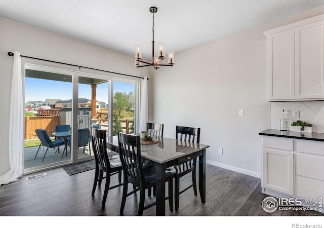 dining space featuring dark wood-style flooring, a chandelier, and baseboards