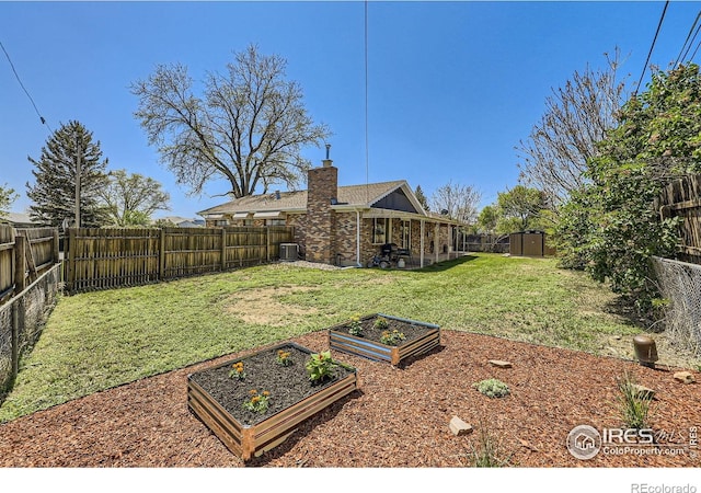 view of yard with a garden, central AC unit, a storage shed, and an outbuilding