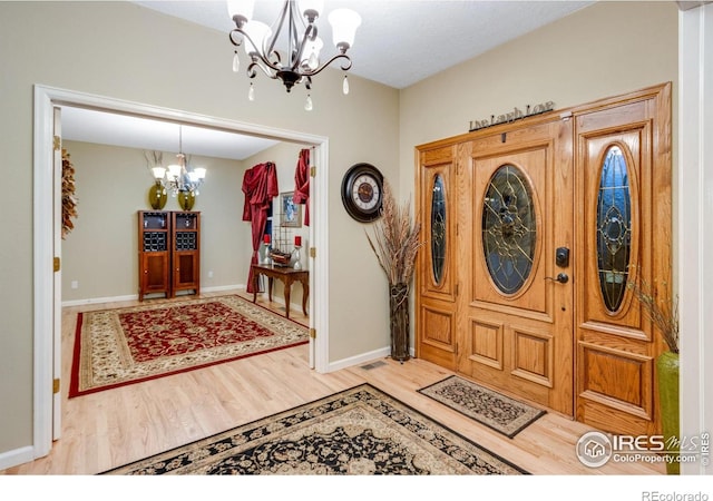 entryway with a chandelier, wood finished floors, and baseboards