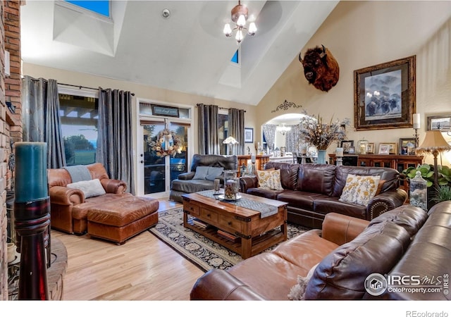 living area featuring a chandelier, high vaulted ceiling, wood finished floors, and arched walkways