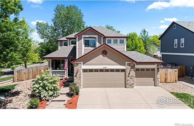 traditional home featuring an attached garage, fence, concrete driveway, a shingled roof, and a porch