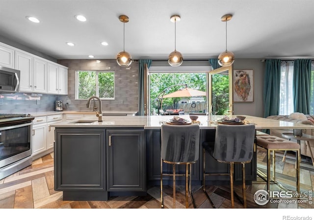 kitchen featuring appliances with stainless steel finishes, a sink, white cabinets, recessed lighting, and decorative backsplash