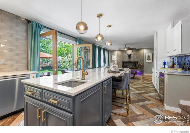 kitchen featuring a sink, dishwasher, white cabinetry, open floor plan, and ceiling fan