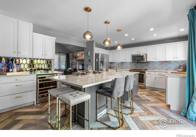 kitchen featuring appliances with stainless steel finishes, wine cooler, white cabinets, a sink, and recessed lighting