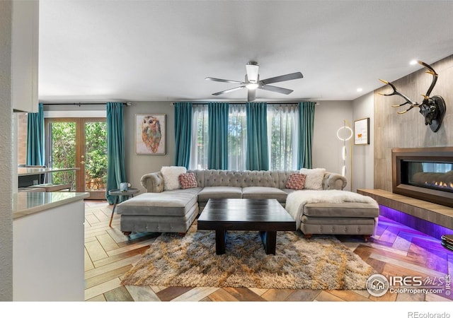 living room with a glass covered fireplace and ceiling fan