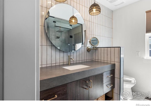 bathroom featuring backsplash, vanity, toilet, and tile walls