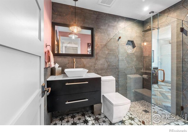 bathroom with tile walls, a stall shower, vanity, and toilet
