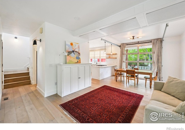 living area featuring light wood finished floors, stairs, and baseboards