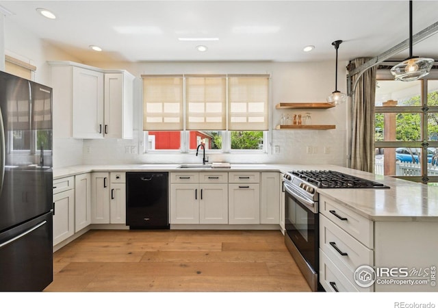kitchen featuring freestanding refrigerator, stainless steel range with gas cooktop, dishwasher, a sink, and tasteful backsplash