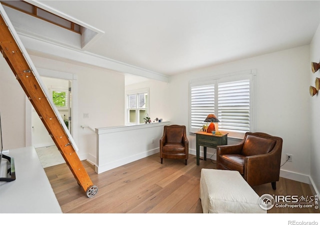 living area with wood-type flooring, baseboards, and an upstairs landing