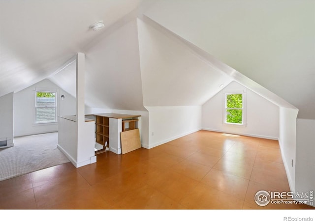 bonus room with lofted ceiling and baseboards