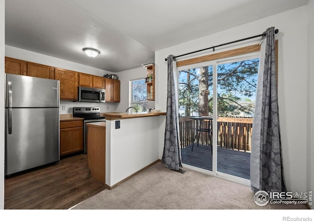 504 Shady Crest Cir, Colorado Springs, CO 80916 - kitchen with stainless steel appliances, brown cabinetry, a peninsula, dark carpet, and baseboards