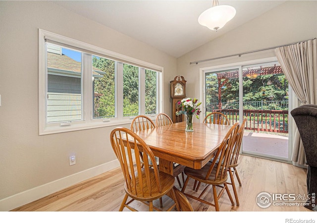 dining area with baseboards, light wood-type flooring, and vaulted ceiling