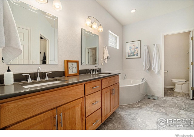 bathroom with double vanity, toilet, a garden tub, and marble finish flooring