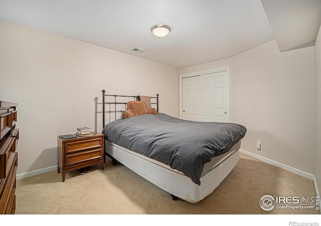 bedroom featuring light colored carpet, baseboards, and a closet