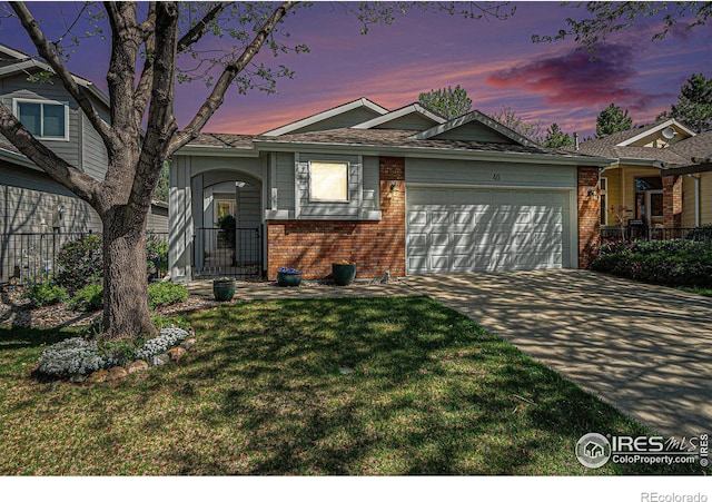 tri-level home with brick siding, an attached garage, a lawn, and driveway